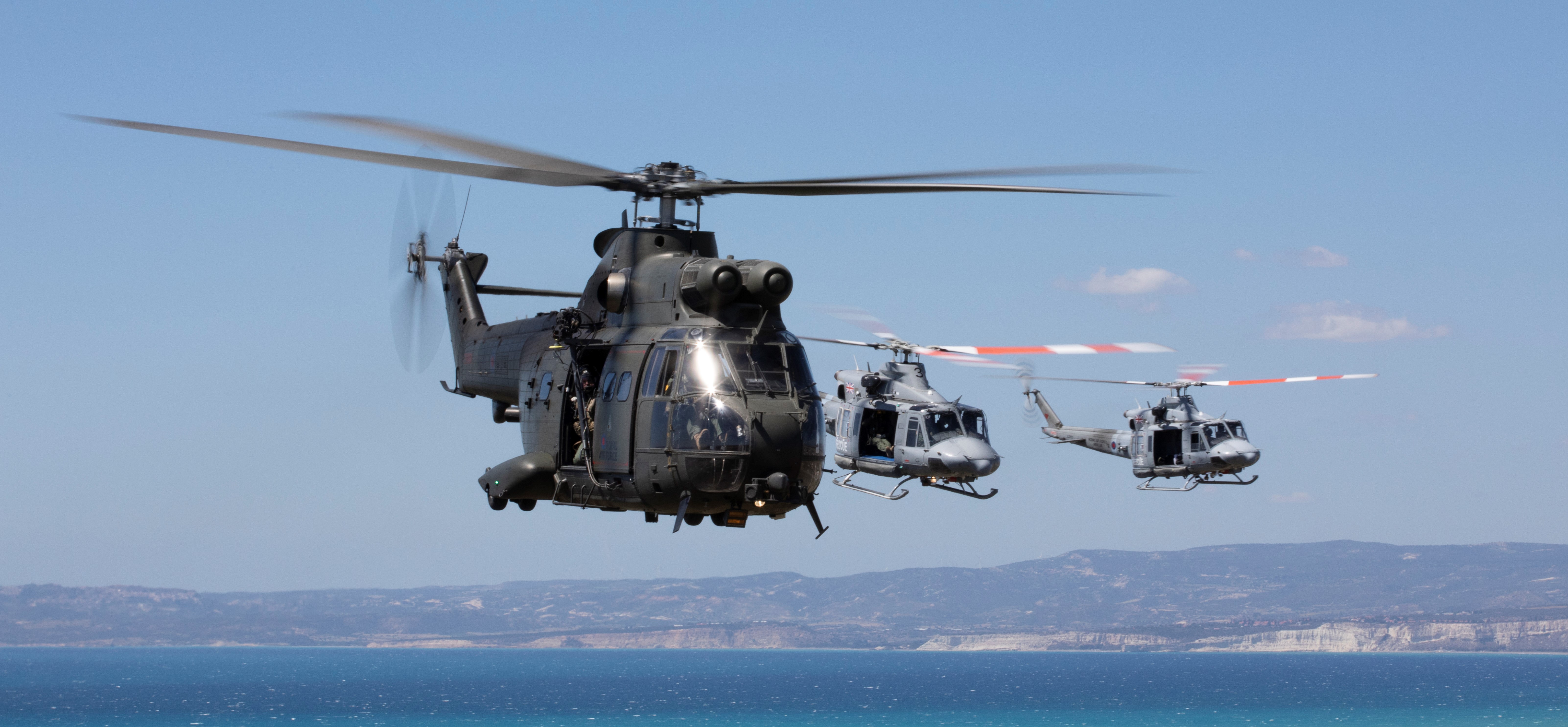 Image shows RAF Puma and Griffin helicopters in flight over the water.